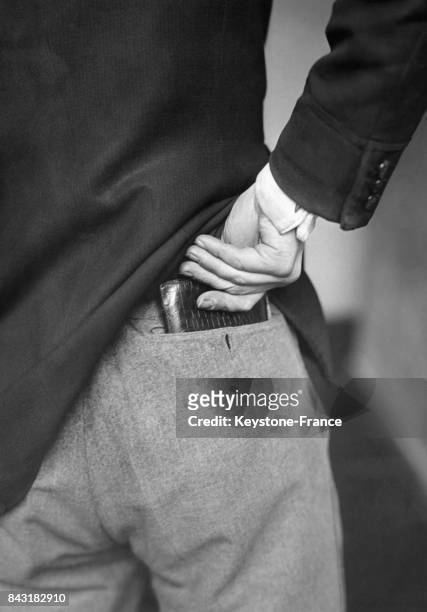 Un homme glisse son portefeuille dans la poche arrière de son pantalon.