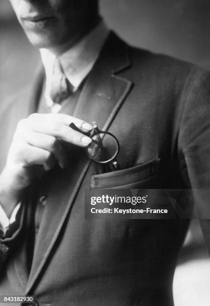 Un homme glisse une paire de lunettes de vue dans la poche avant de son veston.