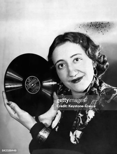 Une femme souriante tient un disque vinyle de la maison de disque Columbia près de son visage.