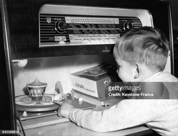 Un jeune garçon observe avec émerveillement les dessins défiler sur un disque tournant sur un tourne-disque le 18 décembre 1958.