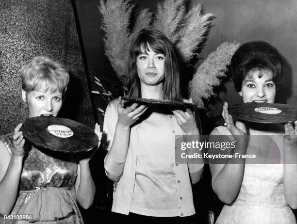 Les trois chanteuses de yé-yé Petula Clark, Françoise Hardy et Rosy Armen croquent dans des disques en chocolat qui leur ont été offerts lors d'un...