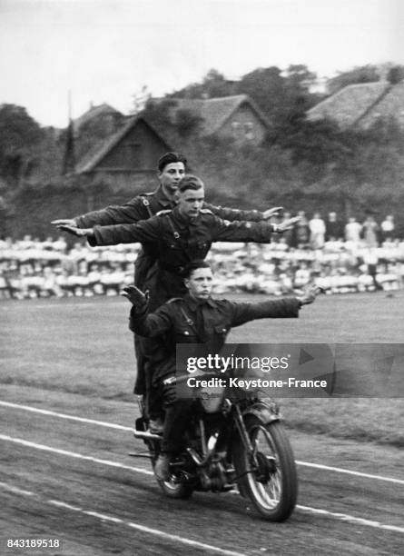 Des garçons membres des Jeunesses Hitlériennes effectuent une démonstration acrobatique à moto le 4 juillet 1937 à Goslar, Allemagne.