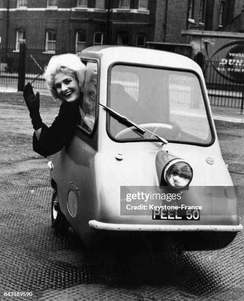 Une femme se penche par la vitre de la Peele P 50, plus petite voiture du monde exposée à Earl's Court le 8 novembre 1962 à Londres, Royaume-Uni.