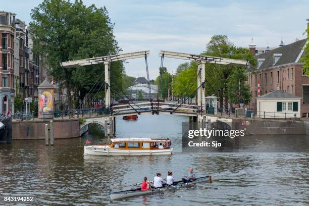 ruderboot und schifffahrt auf dem fluss amstel in amsterdam - fluss amstel stock-fotos und bilder