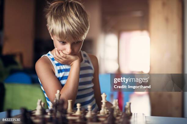 kleine jongen denken over zijn zet in het schaakspel - alleen één jongen stockfoto's en -beelden