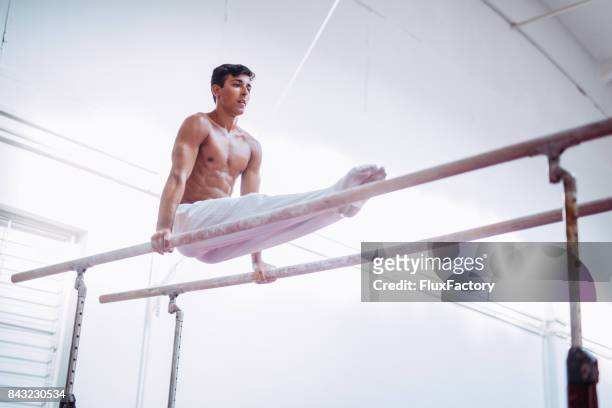 man working out on parallel bars - artistic gymnastics stock pictures, royalty-free photos & images