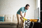 Young man cleaning with a duster