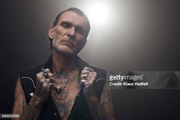 tattoed mid aged man wearing lots of finger rings and looking in camera - toughness man stock pictures, royalty-free photos & images