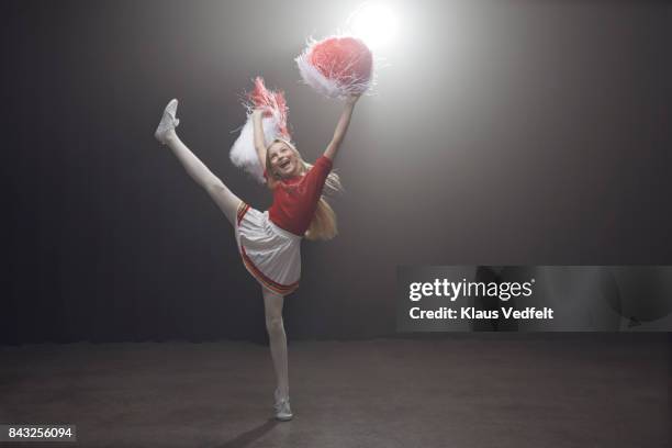 young cheerleader girl with pom poms, standing on one leg - cheerleader high kick stock-fotos und bilder