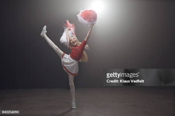 young cheerleader girl with pom poms, standing on one leg - cheerleader high kick fotografías e imágenes de stock
