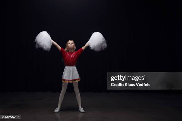 young cheerleader girl with pom poms, looking devoted into the light - pom pom stock pictures, royalty-free photos & images