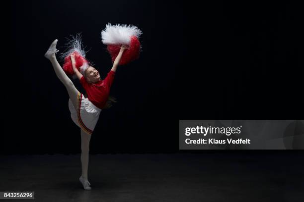 young cheerleader girl with pom poms, jumping with leg stretched - cheerleader high kick fotografías e imágenes de stock