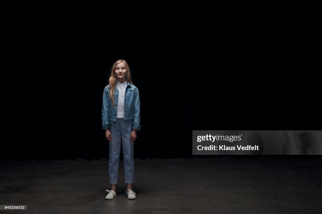 Girl wearing denim jacket, smilling at looking up in the light