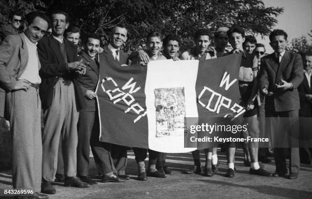Les supporters de Fausto Coppi heureux brandissent un drapeau italien en son honneur après la victoire de leur champion à Varèse, Italie le 2 octobre...