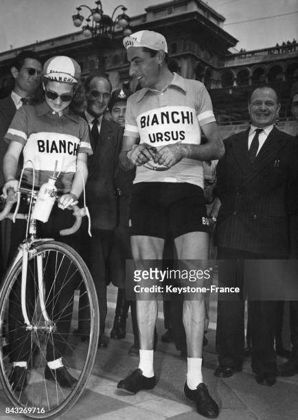 Fausto Coppi avec une jeune admiratrice regardant son vélo avant le départ du Tour à Milan, Italie le 24 mai 1950.