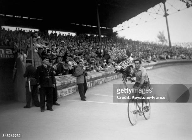 Fausto Coppi, vainqueur du Tour de France, un bouquet de fleurs dans les mains, effectue sur son vélo le tour d'honneur sur la piste du Parc des...