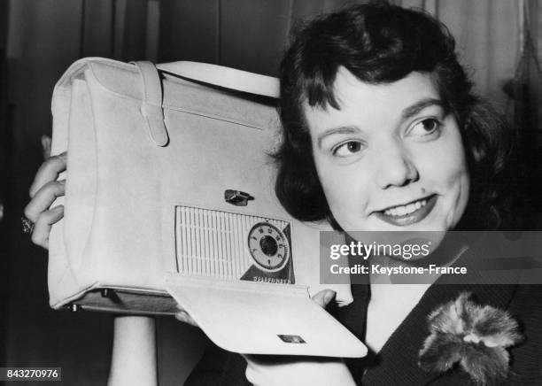 Une femme présente une radio intégrée dans un sac à main en cuir lors de l'exposition sur les biens de l'industrie du cuir le 17 février 1958 à...