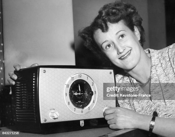 Une femme présente un radio-réveil qui peut également déclencher la minuterie de la bouilloire au Radio Show le 24 août 1954 à Londres, Royaume-Uni.