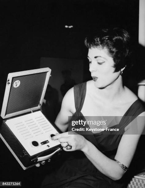 Marie Traynor fait la démonstration du plus petit poste de radio de l'exposition, de la taille d'un sac à main le 24 août 1954 à Londres, Royaume-Uni.