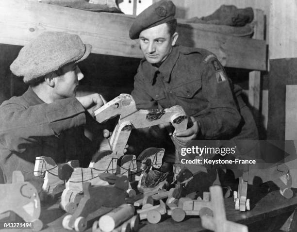 Soldat britannique achetant un jouet à un menuisier, ancien soldat allemand, qui fabrique des jouets à partir de tous les matériaux de récupération,...
