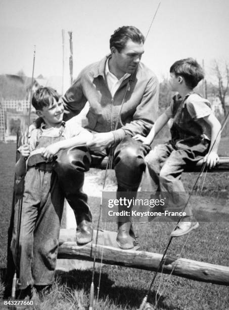 Le champion de boxe allemand Max Schmeling profite d'une pause durant son entraînement pour faire une partie de pêche à la truite avec deux jeunes...