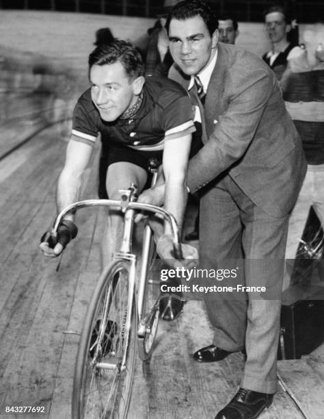 Le boxeur allemand Max Schmeling en visite sur le territoire américain pour un match, donne un coup de main à son compatriote le cycliste Adolf...