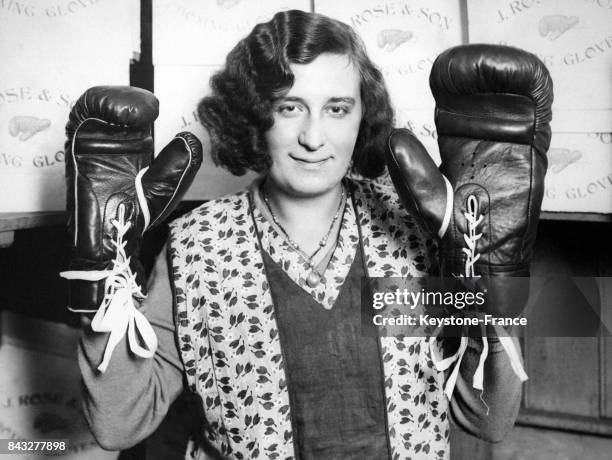 Une employée d'une usine de confection de gants de boxe porte les gants de boxe géants de Primo Carnera le 17 décembre 1930 à Londres, Royaume-Uni.