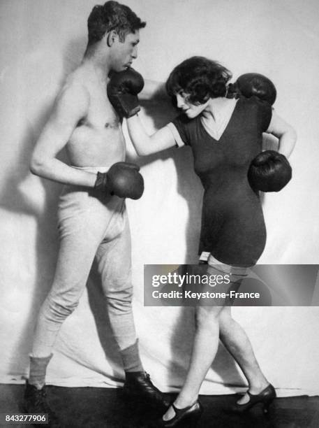 Une boxeuse de 19 ans prometteuse, Madge Baker, s'entraîne à la boxe contre le champion anglais Harry Gold, circa 1930 au Royaume-Uni.