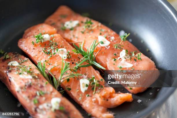 delicious salmon fillet in a pan with garlic and herbs - filete de salmón fotografías e imágenes de stock