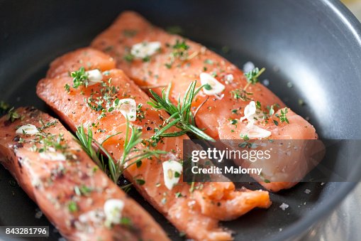 Delicious salmon fillet in a pan with garlic and herbs Delicious salmon fillet in a pan with garlic and herbs