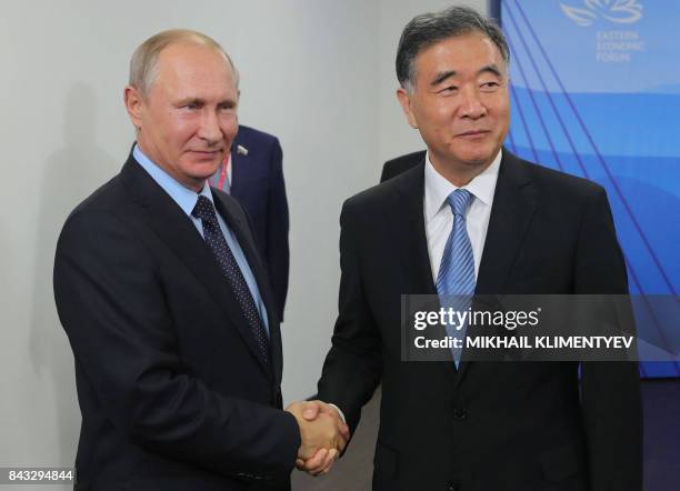 Russian President Vladimir Putin shakes hands with Vice Premier of the State Council of the People's Republic of China Wang Yang during a meeting at...