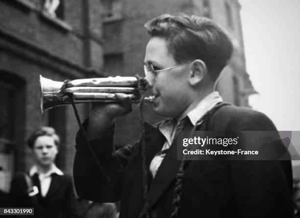 Un garçon de treize ans s'entraîne à souffler dans son cornet comme il sera chargé de le faire lors de la fête de la Victoire en 1946 à Londres,...