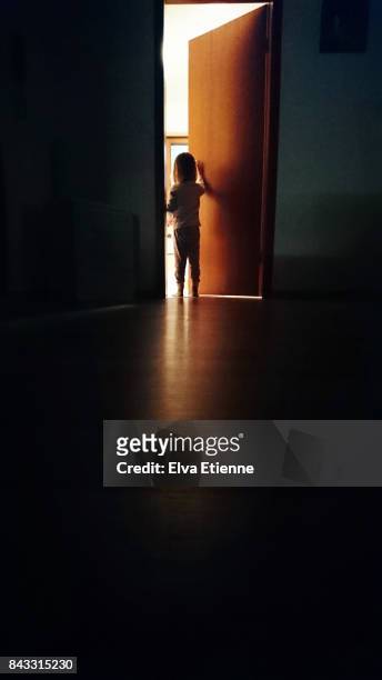 Child in a dark hallway, opening a door into the light