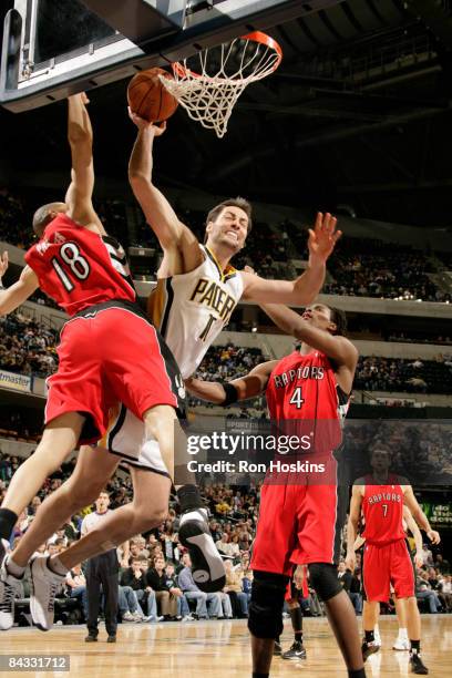 Jeff Foster of the Indiana Pacers drives against Anthony Parker and Chris Bosh of the Toronto Raptors at Conseco Fieldhouse on January 16, 2009 in...