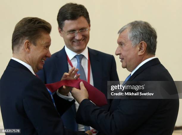 Russian businessman Igor Sechin touches tie of Gazpom CEO Alexei Miller as Energy Minister Alexander Novak looks on during the state council meeting...
