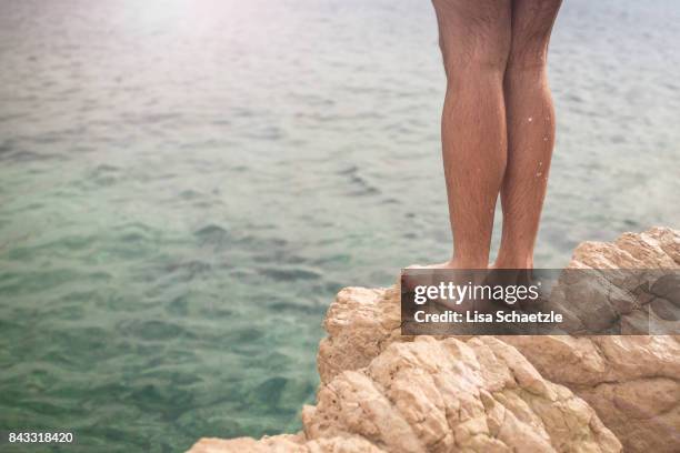 young man jumping off cliff into water - salto desde acantilado fotografías e imágenes de stock