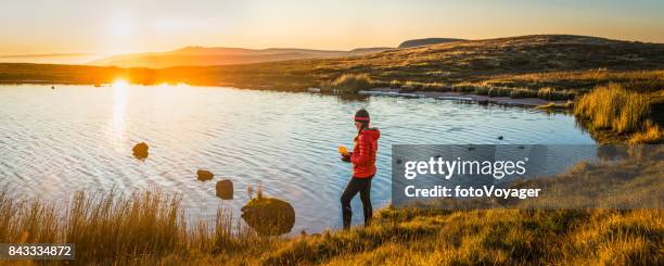 weibliche wanderer füllung wasserflasche vom see sonnenaufgang bergpanorama - brecon beacons stock-fotos und bilder