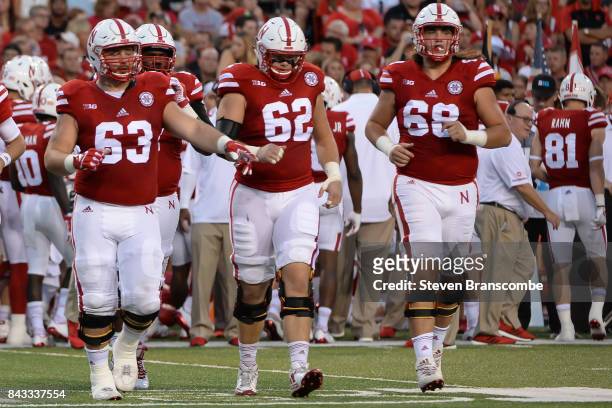 Offensive tackle Tanner Farmer and offensive tackle Cole Conrad and offensive lineman Nick Gates of the Nebraska Cornhuskers enter the field during...
