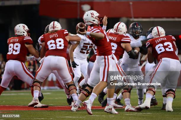 Quarterback Tanner Lee of the Nebraska Cornhuskers attempts a pass behind the offensive line against the Arkansas State Red Wolves at Memorial...