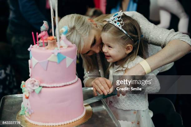 mother helping young girl cut birthday cake - smile woman child stock-fotos und bilder
