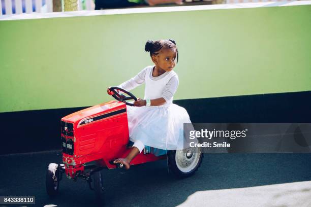 Young girl on miniature toy tractor