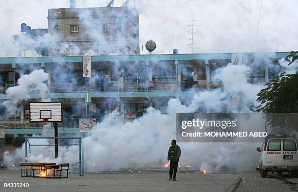 Palestinian man walk away from heavy smoke following an Israeli strike over a UN school in Beit Lahia, northern Gaza Strip early on January 17, 2009....