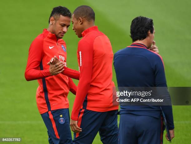 Paris Saint-Germain's French forward Kylian Mbappe shakes hands with Paris Saint-Germain's Brazilian forward Neymar , next to Paris Saint-Germain's...