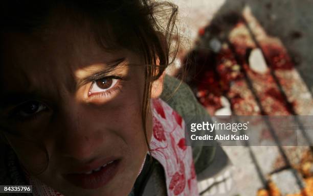 Homeless Palestinian girl stands beside a patch of blood at a United Nations school after it was hit by Israeli shelling on January 17, 2009 in Beit...