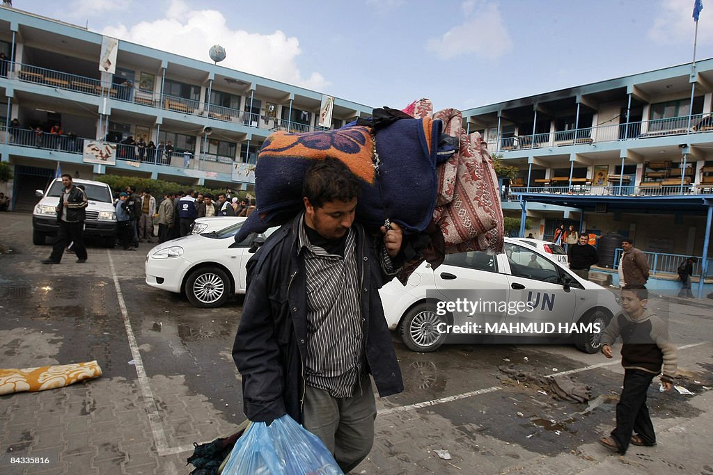 A Palestinian man carries blankets and m