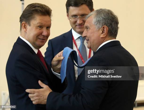 Russian businessman, Rosneft President Igor Sechin looks on Gazpom CEO Alexei Miller who touches his tie as Energy Minister Alexander Novak smiles...