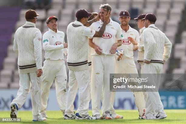 Rikki Clarke of Surrey is congratulated by Jade Dernbach after taking the wicket of Liam Dawson of Hampshire during day two of the Specsavers County...