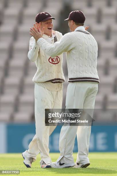 Ollie Pope of Surrey celebrates with Gareth Batty after taking a catch off the bowling of Rikki Clarke to dismiss Liam Dawson during day two of the...