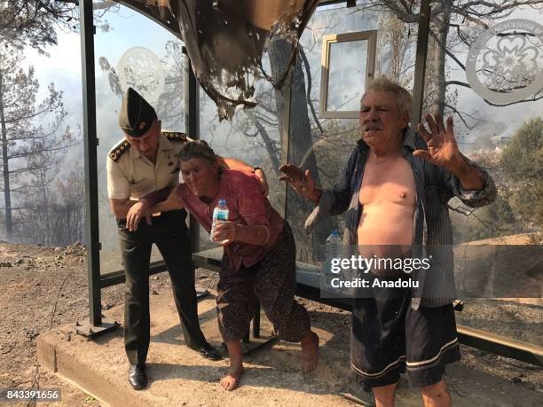 Akbuk neighborhood resident Ismail Cinar and his wife Arzu Cinar gestures as Gendarmerie Colonel Numan Oksuz tries to calm them down before...