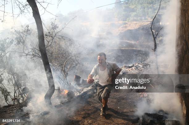 Man runs through the fire smoke as firefighters try to extinguish fire in Akbuk neighborhood in Mugla's Mentese district, Turkey on September 6,...